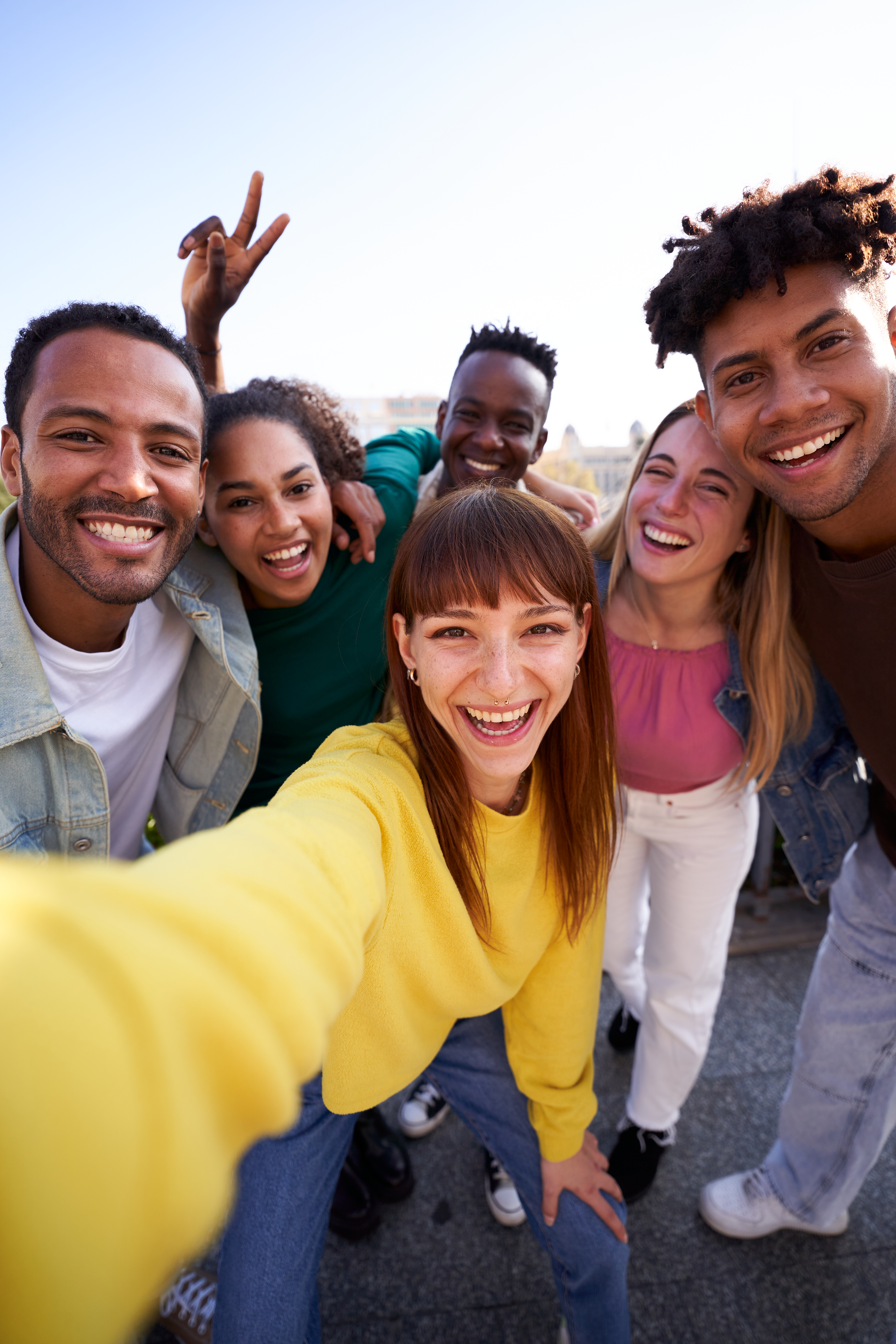 Group of diverse youth taking a selfie outdoors, having fun in sunny day.