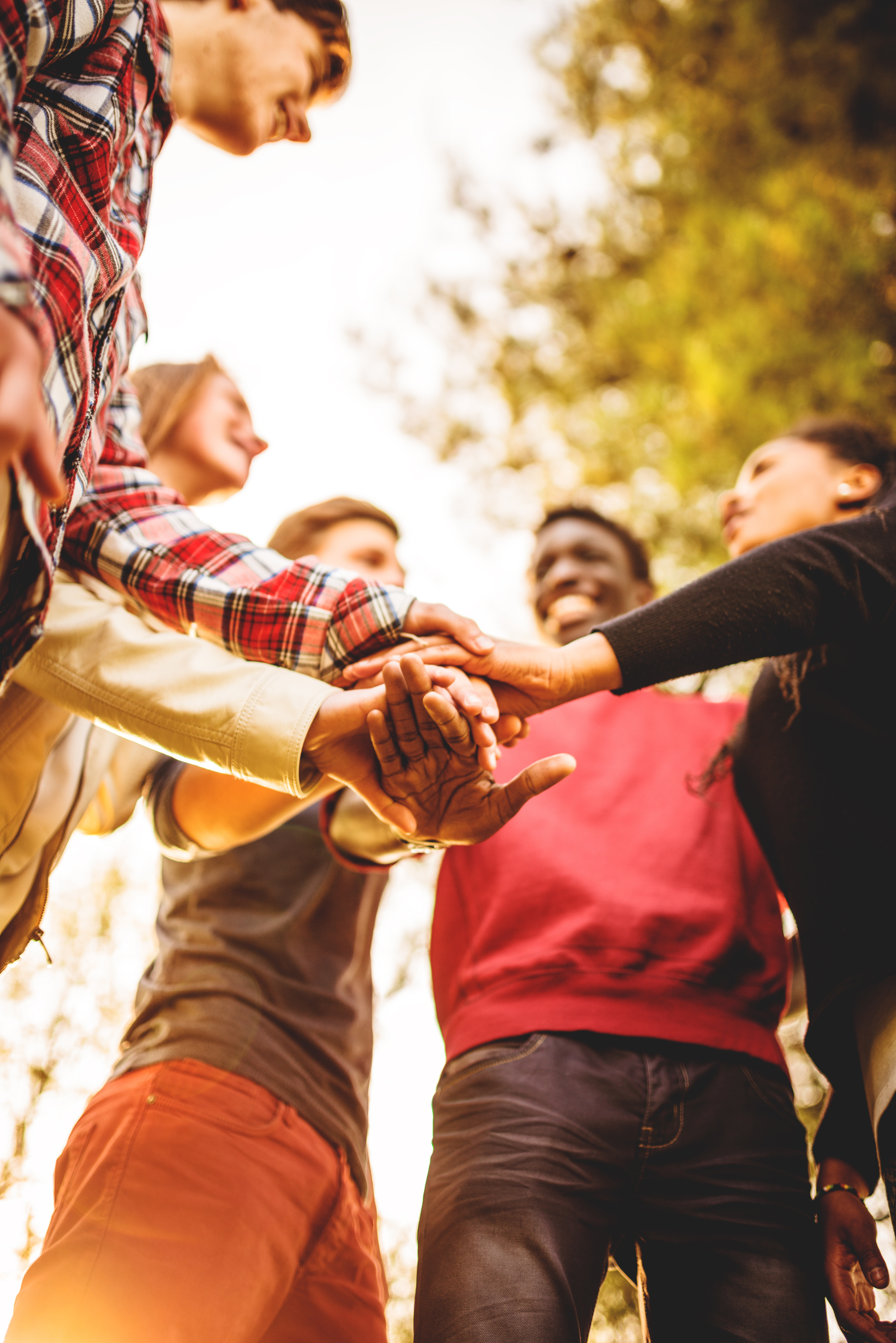 Group of people standing in a circle with their hands stacked together in a team gesture.