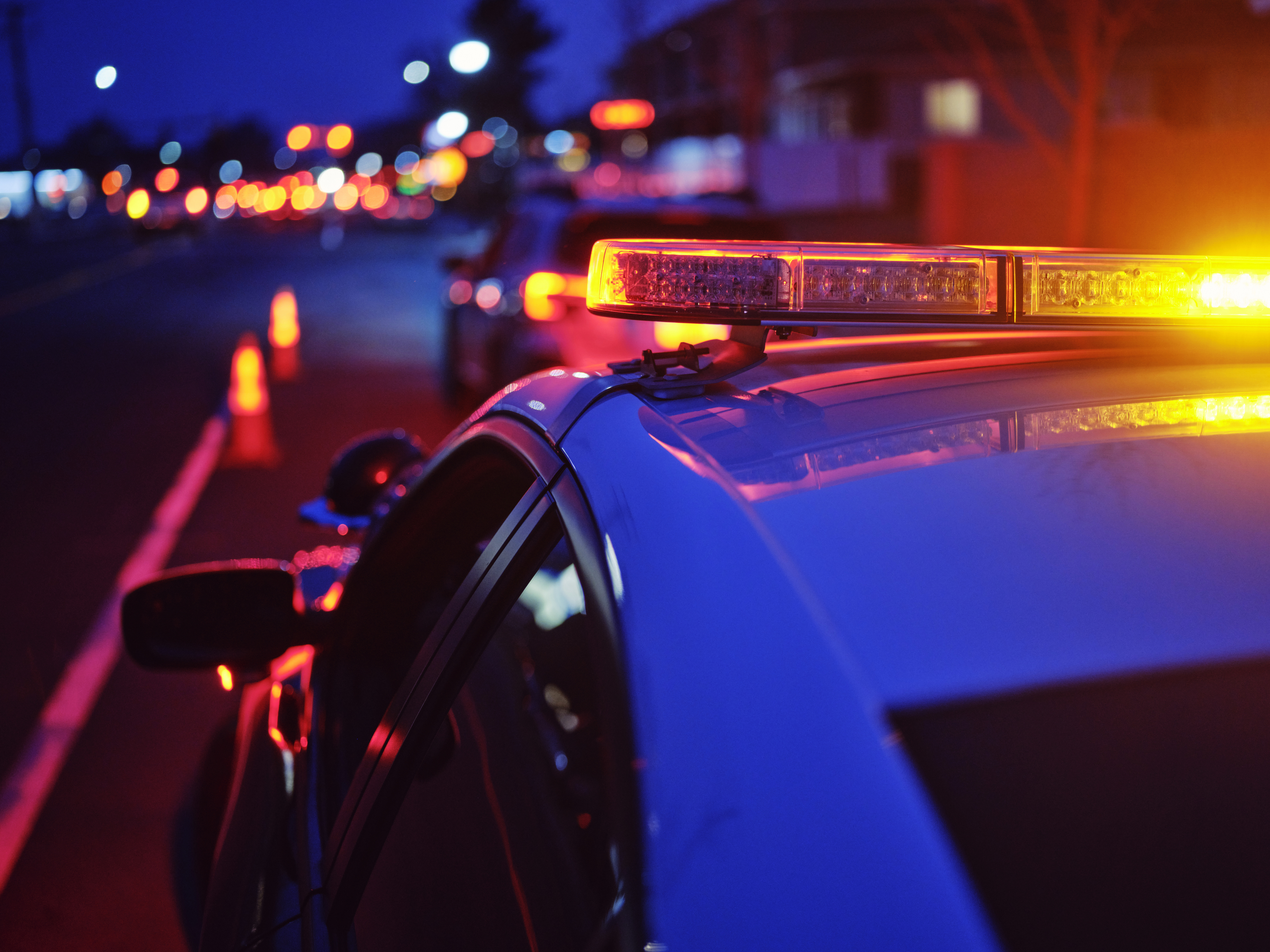 A police car with flashing lights pulled over on the side of the road.