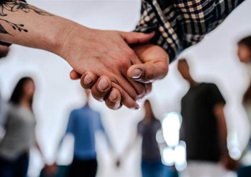 Close-up of people holding hands supporting each other during a group session.