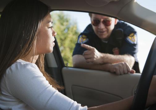 Driver speaking with a police officer at a car window.