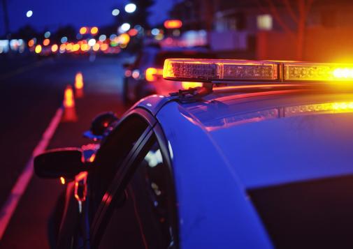 A police car with flashing lights pulled over on the side of the road.
