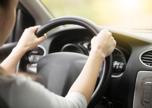 Two hands gripping a steering wheel in a car.