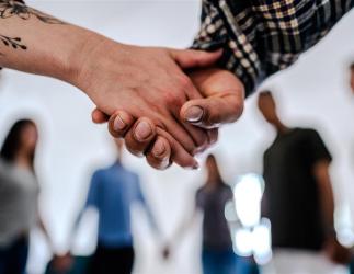 Close-up of people holding hands supporting each other during a group session.