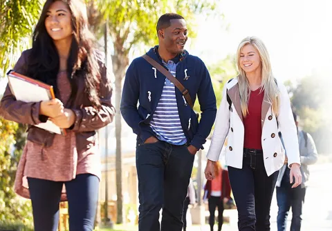 Two students walking on a campus, appearing to be having a pleasant time