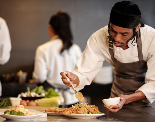 Chef preparing a dish while other cooks work in the background. 