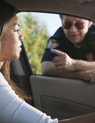 Driver speaking with a police officer at a car window.
