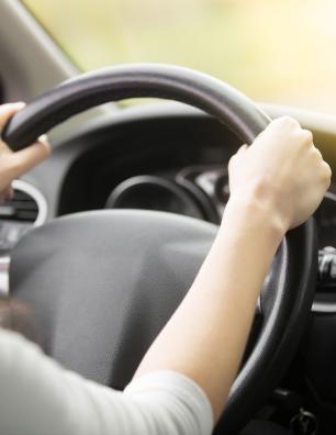 Deux mains agrippant le volant d’une voiture.