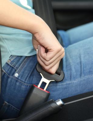 Personne qui attache sa ceinture de sécurité.