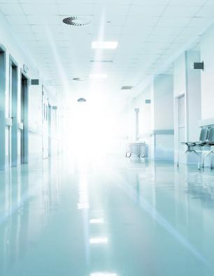 Corridor d’hôpital lumineux et vide avec un plancher bien ciré et des portes des deux côtés.