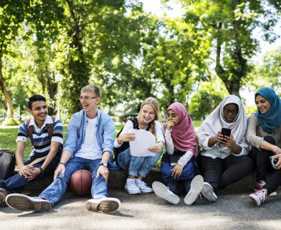 Groupe d'adolescents assis sur un trottoir.