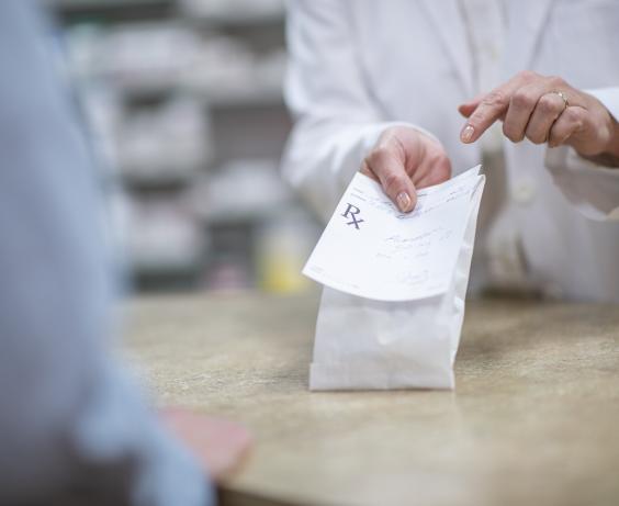 Pharmacist holding medication with a prescription. 