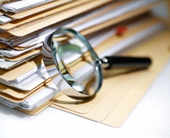 pile de documents à côté d'une loupe.