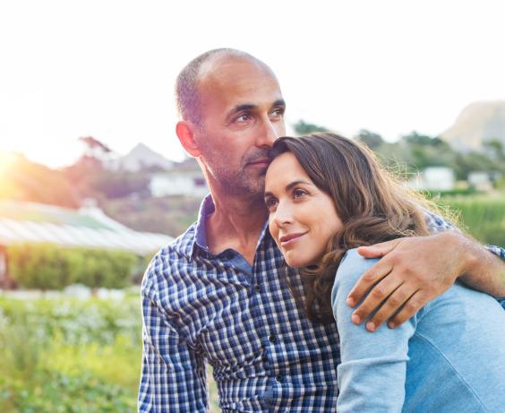 Two people sitting outdoors, with one leaning their head on the other’s shoulder.